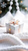 white gift box with a delicate gold ribbon rests on a fluffy blanket photo