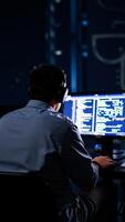 person wearing headphones focuses on code displayed on a computer monitor photo