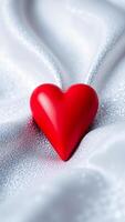 single red heart rests on a sparkling silver surface photo