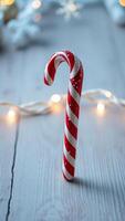 candy cane resting on a white wooden surface with festive decorations photo
