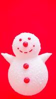 white snowman figurine with red buttons on a red background photo