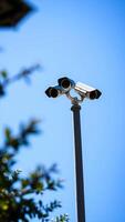 triple-lens security camera mounted on a pole against a blue sky photo