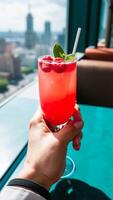 hand holds a glass pink raspberry drink with mint garnish photo