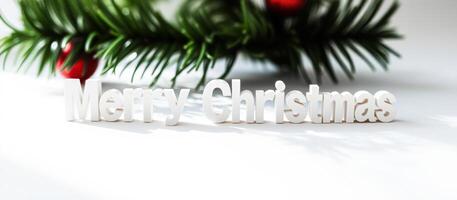 white 3d letters spell out 'merry christmas' with a blurred background evergreen branches red ornaments photo