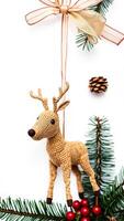 crocheted reindeer ornament hanging with pine branches a golden bow photo