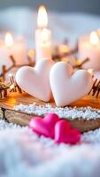 two white hearts on a wooden surface with warm candlelight photo