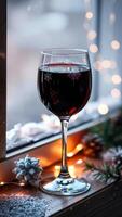 vaso rojo vino con copo de nieve diseños crea un festivo atmósfera en un antepecho foto