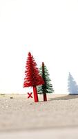 two small artificial trees one red one green stand on a textured surface photo