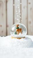 glass snow globe with a deer figurine falling snowflakes photo