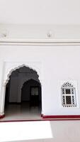 white tiled floor with a maroon border leads into a dark room with a patterned window photo