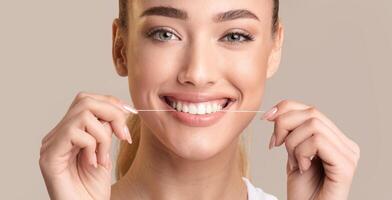 Teeth Flossing. Smiling Woman Using Tooth Floss Cleaning And Caring For Perfect White Teeth Posing Over Beige Background. Panorama photo