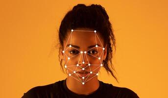 African American lady stands against a warm amber background while facial recognition markers are displayed on her face, highlighting facial features and expressions in a modern technological photo