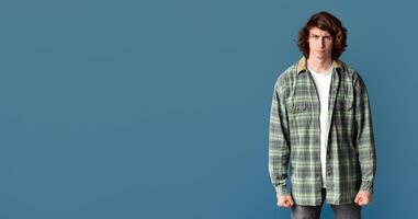 Millennial guy clenching his fists in anger and frowning on turquoise background photo