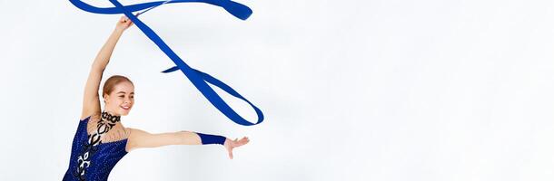 Rhythmic gymnastics exercises. Young slender girl practicing with red ribbon on white background photo