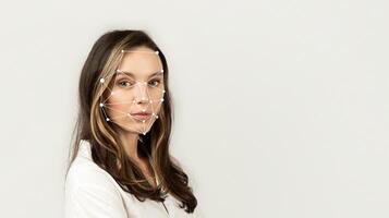 A woman poses with facial recognition markers displayed on her face while looking directly at the viewer. The background is minimal, emphasizing her features and the technology used. photo