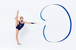 Gymnastic moves. Slender young woman in leotard doing exercises with ribbon on white background, copy space photo