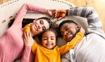 Smiling multiracial millennial family lie on the floor top view, panorama photo