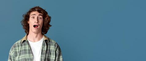 Shocked teenage guy shouting WOW on color studio background photo