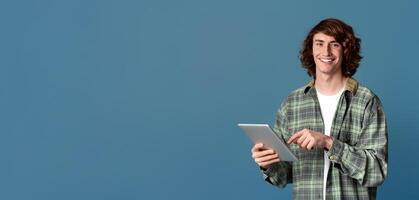 Communicating online. Portrait of young hipster using tablet computer on color background photo