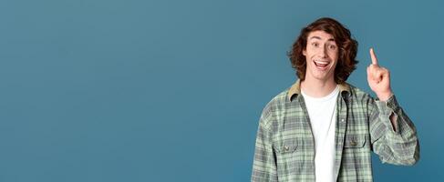 Creative idea. Cheerful millennial guy showing EUREKA gesture on turquoise background photo