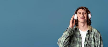 Funky guy with closed eyes enjoying his favorite music in headphones, turquoise background photo