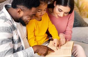 Multiracial parents helping daughter read book. Isolation at home during quarantine photo
