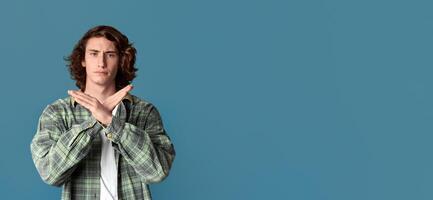 Expressing denial. Serious millennial guy showing STOP or TIME OUT gesture on color background photo