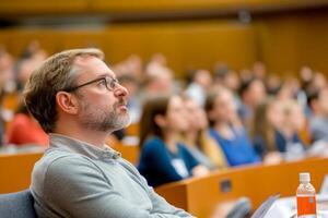 A focused attendee listening intently during a lecture in a large auditorium photo