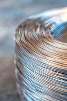 Close-up of a tightly coiled steel wire with detailed metallic textures and soft lighting reflections. photo