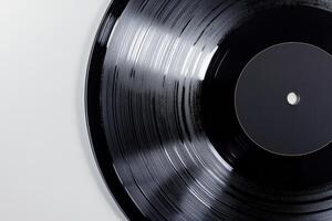 A close-up of a vinyl record with a blank black label on a white background, showcasing its grooves and glossy finish photo