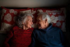 Elderly couple sharing a tender moment while lying together on a cozy bed at home in soft evening light photo