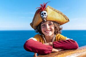 A young pirate with a feathered hat gazes over the ships railing at the ocean during a sunny day photo