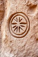 Ancient symbolic patterns carved into stone with worn textures and muted colors representing ancestral wisdom photo