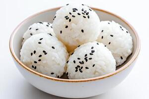 Delicate white rice balls topped with black sesame seeds in a minimalist style on a soft light background photo