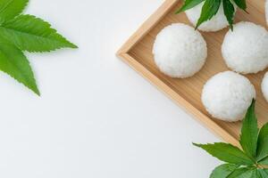 Minimalist display of rice balls garnished with fresh shiso leaves on a wooden tray against a clean white background photo