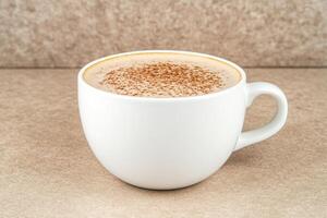 Enjoy a warm cup of steaming coffee with rich foam on a cozy beige table setting photo