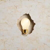 A light bulb embedded in a textured stone surface illustrating creative ideas emerging from calm reflection photo
