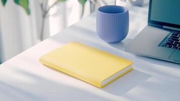 A stylish workspace featuring a mustard yellow notebook and lavender cup with natural light illuminating the setup photo