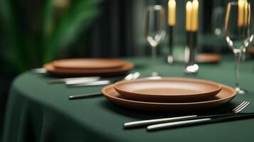 Elegant dining table set with dark green tablecloth and terracotta plates, perfect for an evening gathering photo