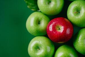 A single red apple stands out among green apples on a minimalistic background representing uniqueness and diversity photo