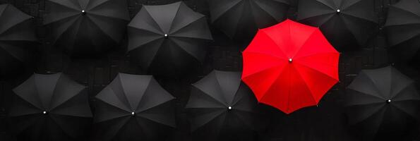 A vibrant red umbrella stands out among a multitude of black umbrellas in a stylish urban setting photo