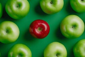 A striking red apple stands out amongst green apples on a minimalistic background showcasing uniqueness photo