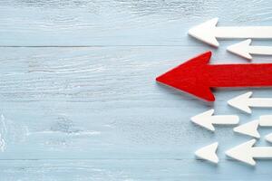 A striking red arrow moves against a group of white arrows emphasizing the concept of defiance in a minimalistic design photo