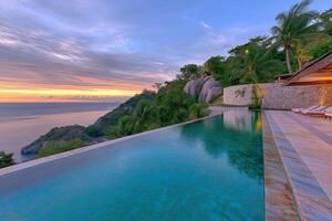 Relaxation at a high-end resort infinity pool with sunset view over the ocean and palm tree reflections photo