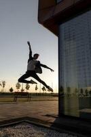 young attractive dancer in casual cloth doing ballet jump on the urban background. photo
