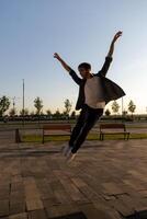 young attractive dancer in casual cloth doing ballet jump on the urban background. Contemporary dance, modern choreography. photo
