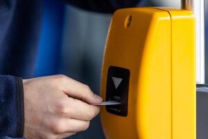 Young man hand inserts the bus ticket into the validator, validating and ticking photo