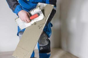 Tiler worker placing or tiling gray ceramic tile in the position over adhesive glue with lash tile leveling system, renovation or recontruction, concept of building photo