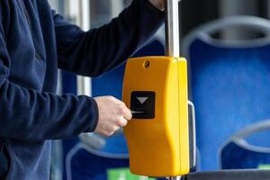Young man hand inserts the bus ticket into the validator, validating and ticking photo