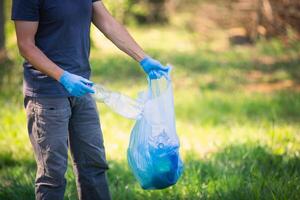 Man picking up plastic bottle, garbage collecting in forest cleaning planet, help garbage collection charity environment, garbage in the forest photo